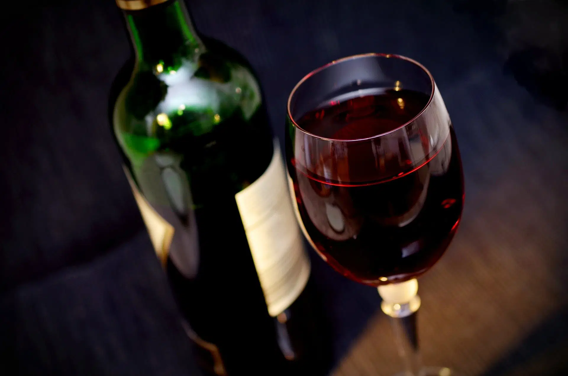 Glas Rotwein neben Weinflasche