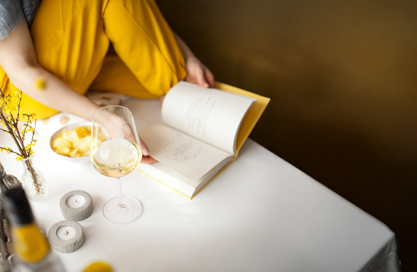 Ein Glas Weißwein neben einem aufgeschlagenen Weinbuch am Tisch